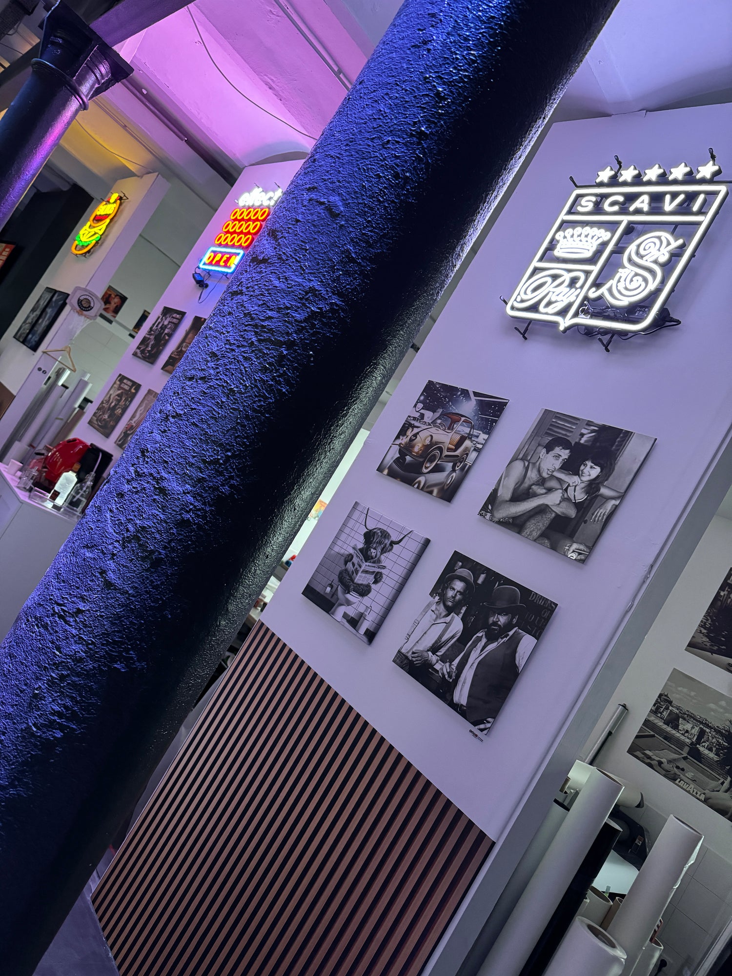 Wand mit Kunstbildern und leuchtenden Neonschildern in einem Raum mit moderner Beleuchtung und dekorativer Atmosphäre