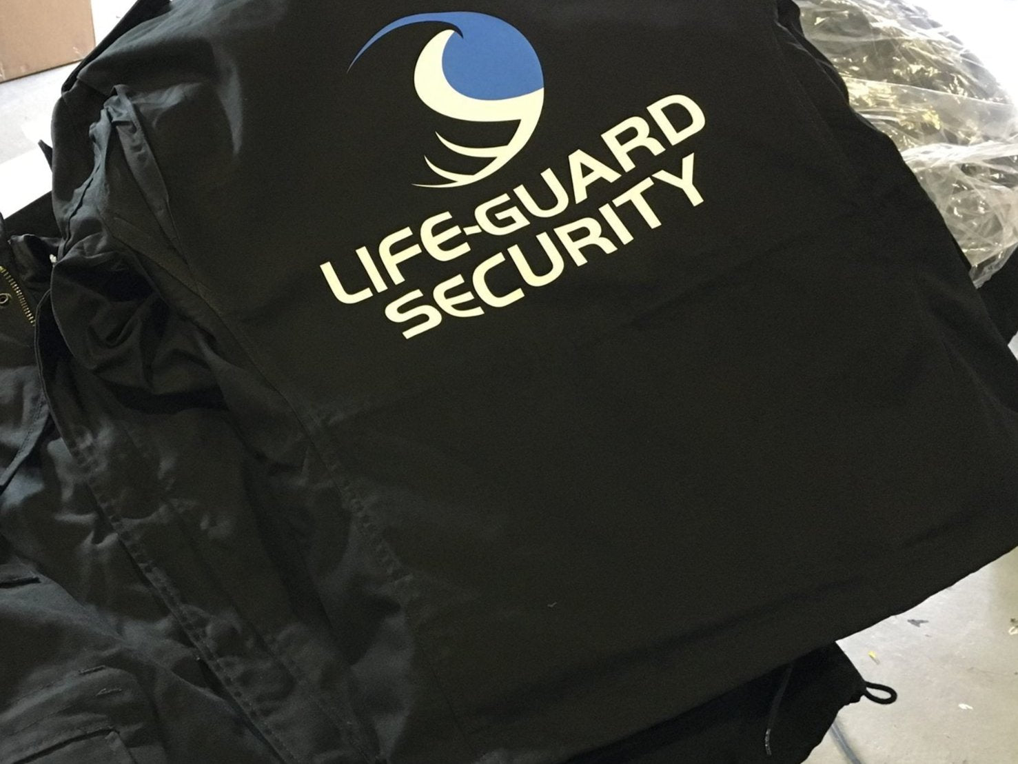 Schwarze Jacke mit "Life-Guard Security" Logo bedruckt, ideal für Sicherheitsfirmen
